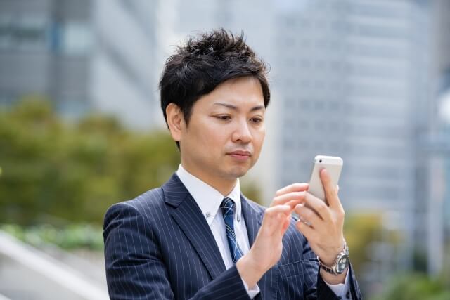 男性がスマホで問い合sている